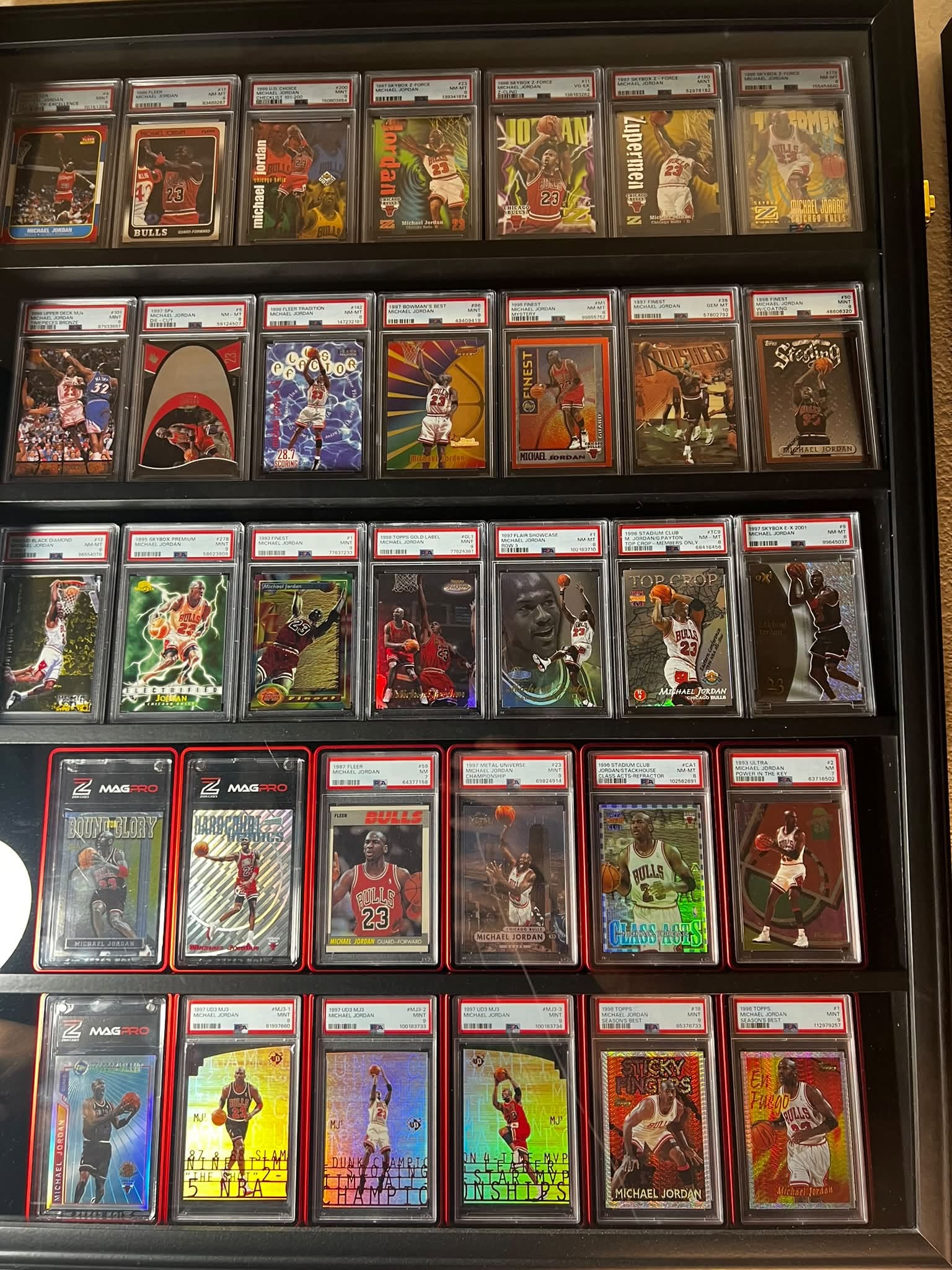 Display case of graded 1990s Michael Jordan basketball cards, five shelves of slabbed cards